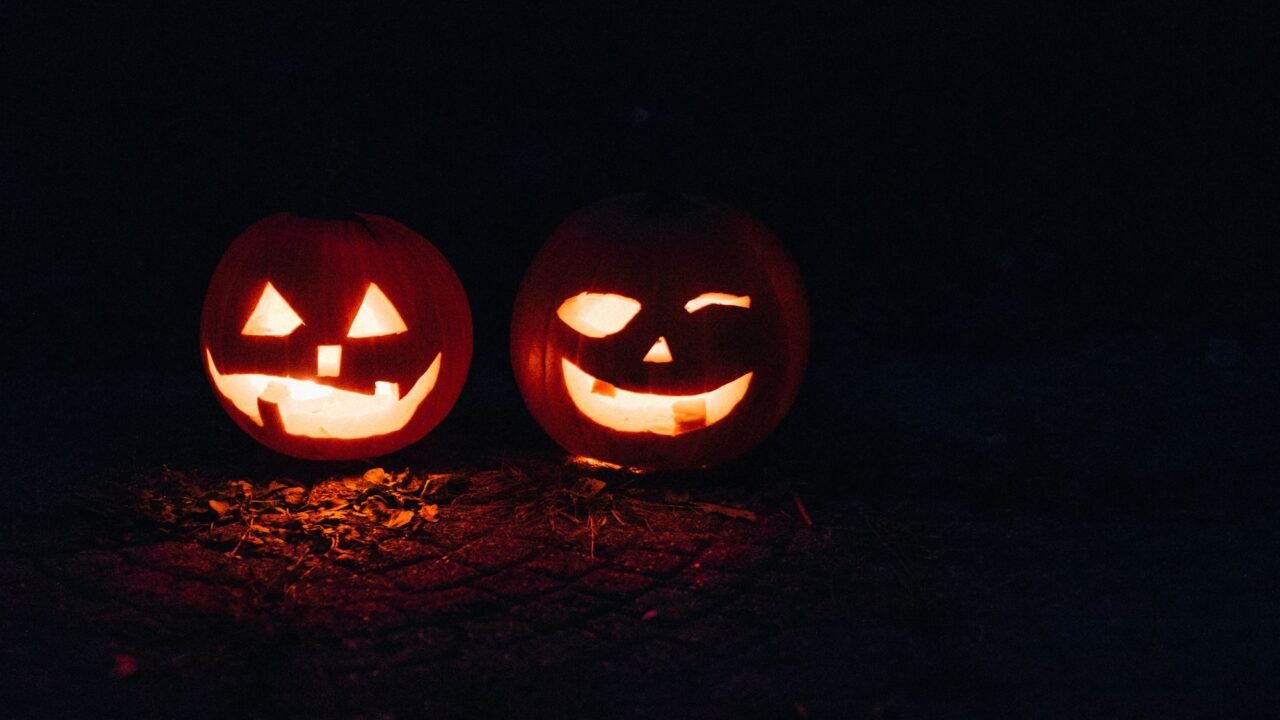 Two carved jack-o'-lanterns glowing in the dark on Halloween night.