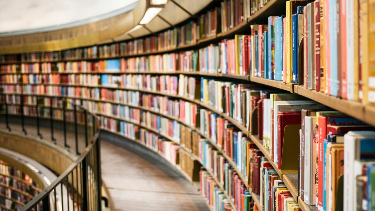 Rows of colorful books on curved shelves in a library.
