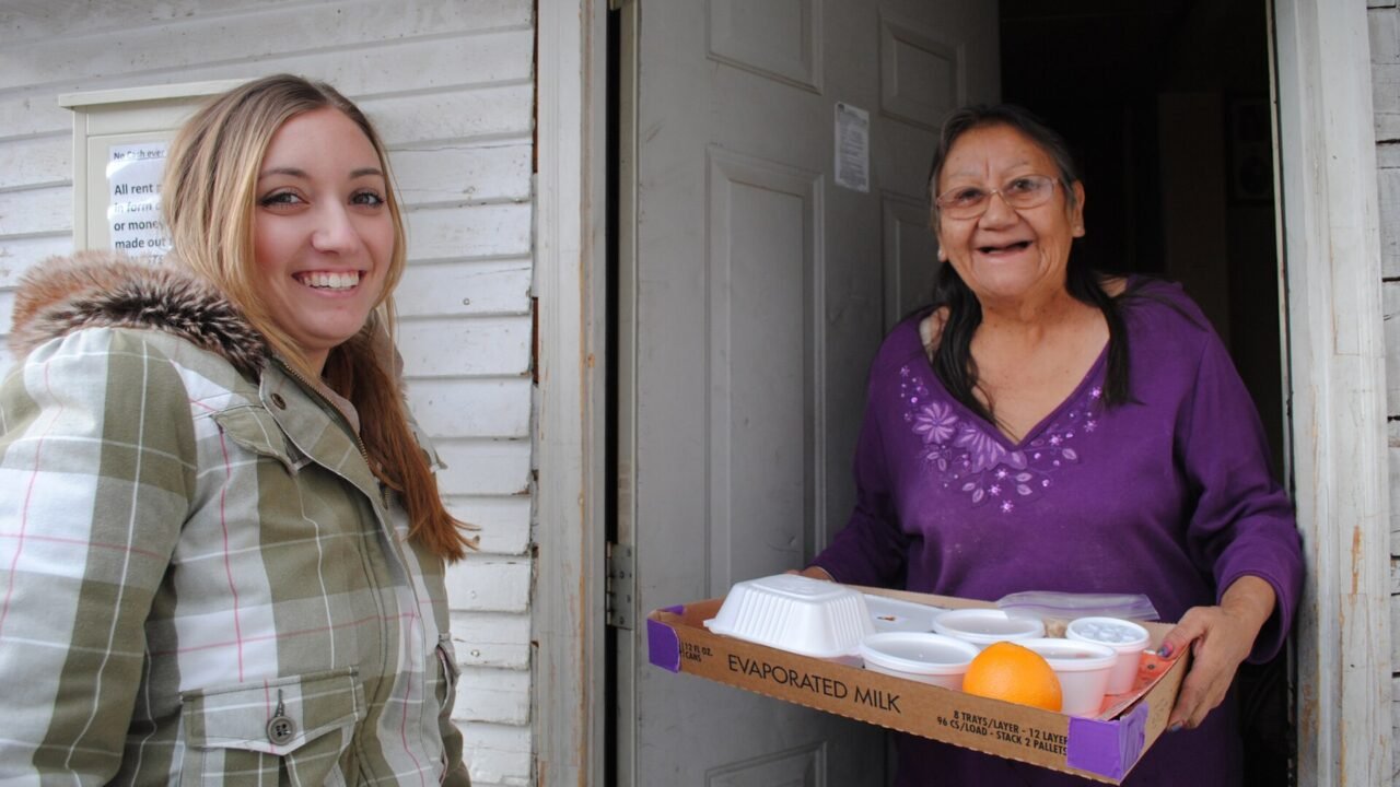 A volunteer delivering a Meals on Wheels meal